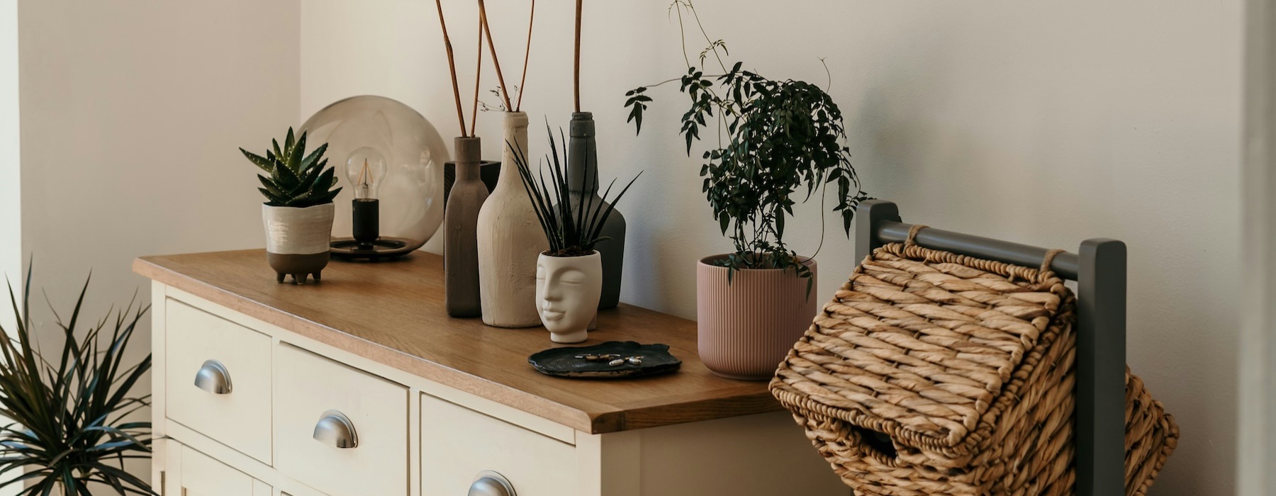 a room with a dresser, baskets and plants