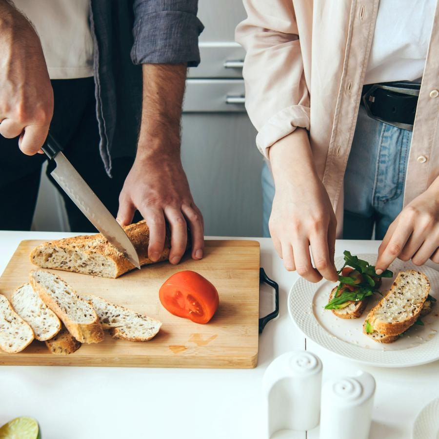 a couple of people cutting a sandwich